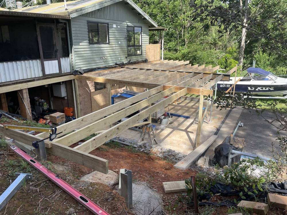 Cleared ground beside a house with a new deck frame going up